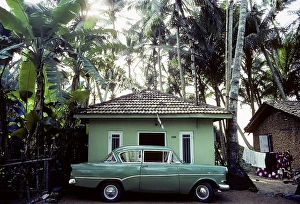 Green vintage car parked in front of a small