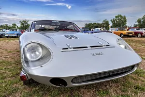 Grey sporty vintage car with retro design in a meadow under a cloudy sky