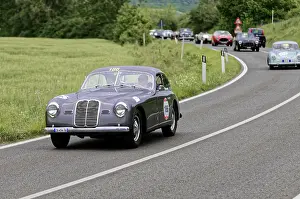 Grey vintage car with race number on a country road