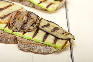 Grilled vegetables on rustic bread over wood table