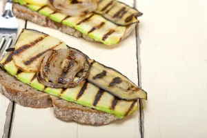 Grilled vegetables on rustic bread over wood table