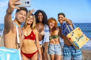 Group of cheerful multi ethnic friends taking a selfie on the beach