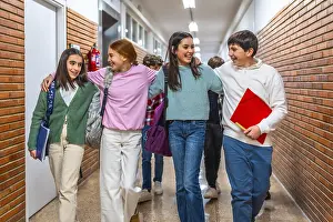 Group of cheerful students walking together in school hallway