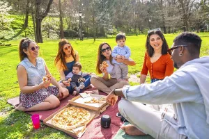 Group of friends and their children having fun at a picnic in a park