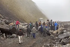 A group of people is active together on a rocky road in a foggy mountain landscape