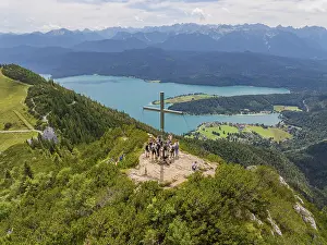 Group of people on a mountain top with a view of a lake and surrounding mountains