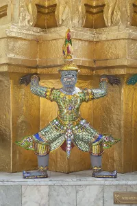 Guardian statue on the base of a golden chedi at Wat Phra Kaeo