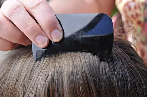 Hair being combed with a small-tooth comb in search of head lice and nits