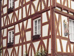 Half-timbered building with red struts and wall relief of a religious figure on the facade