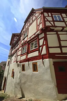 Another half-timbered house with red beams and traditional design under a blue sky in Bad Wimpfen