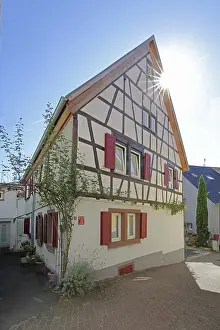 Half-timbered house with red shutters against the light