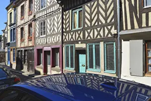 Half-timbered houses are reflected on the roof of a car
