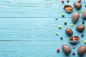 Halves of chocolate eggs, sweets on blue wooden table