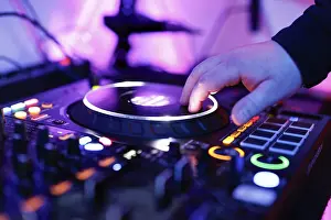 Hand of a DJ on a mixing desk, also called DJ controller or DJ console