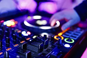Hand of a DJ on a mixing desk, also called DJ controller or DJ console