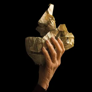 A hand grips a crumpled newspaper