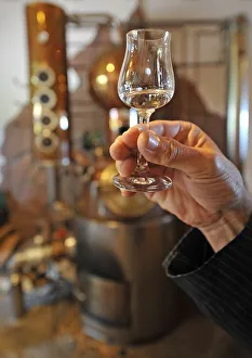 Hand holding jigger in front of a distillery