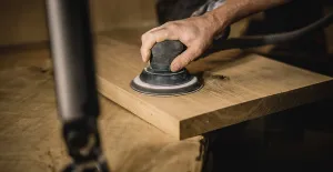 Hand sanding a wooden plank in a workshop