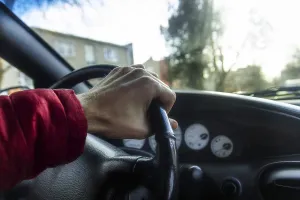 Hand on steering wheel in red jacket