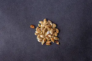 A handful of dry pumpkin seeds on a dark background