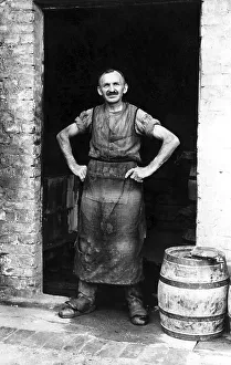 Handicraft, barrel maker stands in the door of his workshop