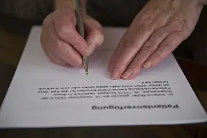 Hands of a 82-year-old woman signing a living will