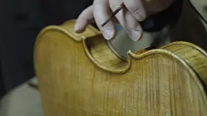 Hands crafting a violin demonstrating detailed craftsmanship and texture