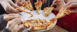 Hands eagerly reaching for remaining pizza slices on a plate