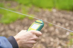 Hands holding a device for an electrical measurement on a wire