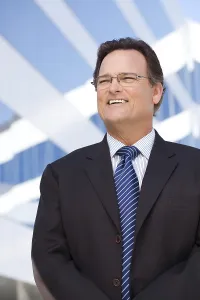 Handsome businessman smiling in suit and tie outside of corporate building