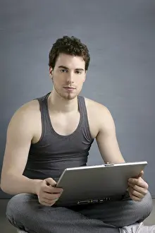 Handsome student young man sit working on laptop over gray background