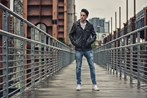 Handsome young man standing outdoors in urban environment on metal stairs