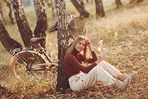 Happy active young woman riding vintage bicycle in autumn park at sunset