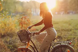 Framed Print : Happy active young woman riding vintage bicycle in autumn park at sunset