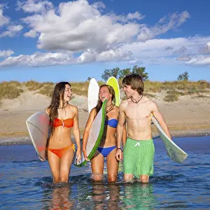 Happy beautiful teen surfers talking on beach shore smiling