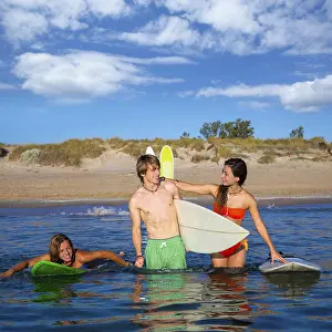 Happy beautiful teen surfers talking on beach shore smiling