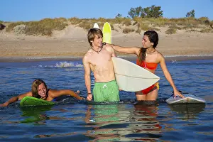 Happy beautiful teen surfers talking on beach shore smiling