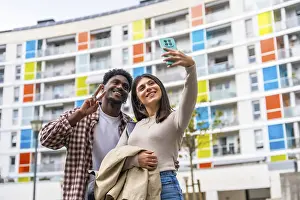 Happy diverse couple smiling and posing for a smartphone selfie