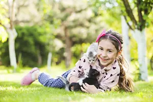 Happy girl with small kittens. Cute girl playing with cat on natural background