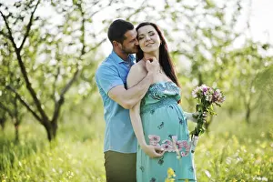 Happy pregnant couple at turquoise dress on the garden