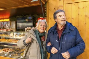 Happy senior couple strolling arm in arm at a traditional christmas market