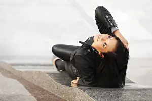 Happy young woman lying on the sidewalk