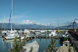 Category Mountain Landscapes Prints: A harbour with numerous boats, mountains in the background and a clear sky