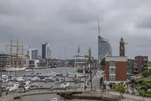 Harbour view with sailing boats and modern skyscrapers on a cloudy day
