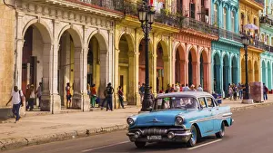 Havana, Cuba on December 22, 2015: A blue oldtimer taxi is driving through Habana Vieja in front of a colorful facade