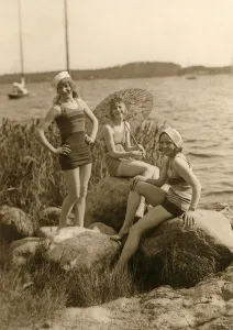Having fun in the 1930s. Three young women on the beach dressed in the 1930s fashion of bathing suits
