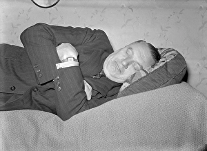 Having a nap in the 1940s. A tired man is lying on the bed having a nap