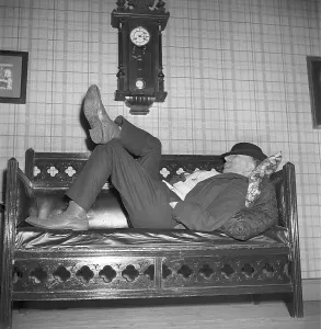Having a nap in the 1940s. A tired man is lying on the sofa having a nap