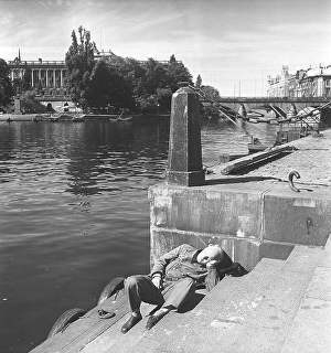 Having a nap in the 1940s. A tired postman has fallen asleep on the steps by the quay