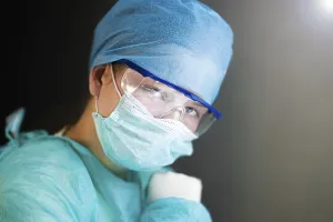 A healthcare worker in safety gear looking determinedly ahead